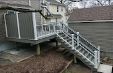 Completed gray deck with white railing and a long stair run