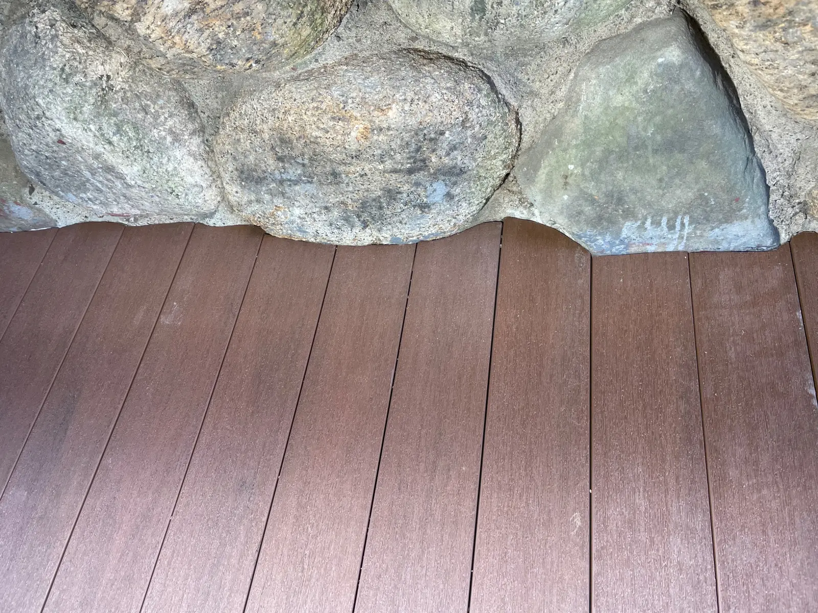 Composite decking custom cut to meet irregular stonework