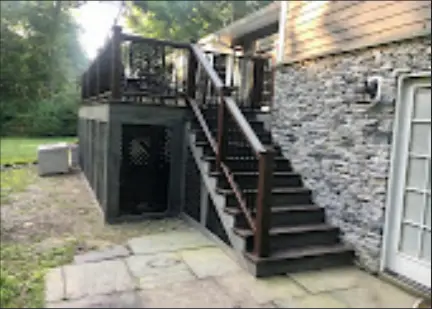 Deck stairs beside a stone-accented exterior wall