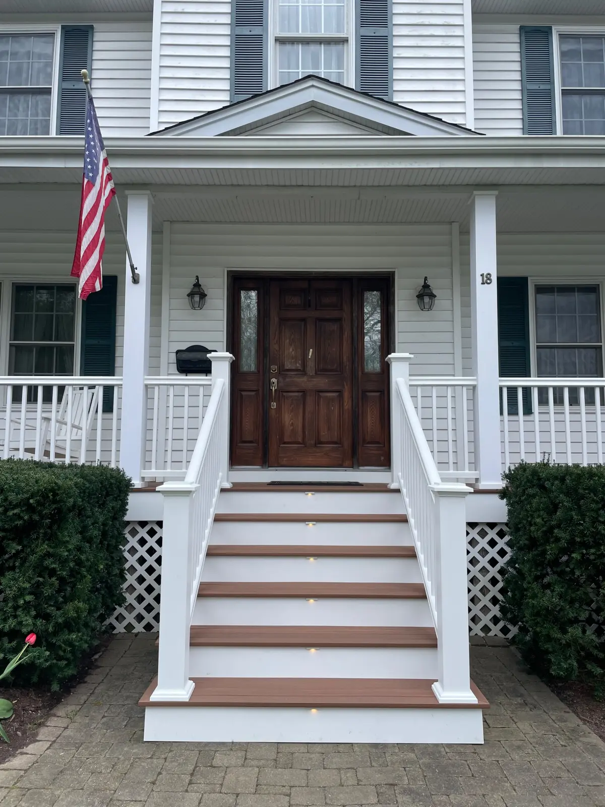 Completed front entry stairs with composite treads and white railing