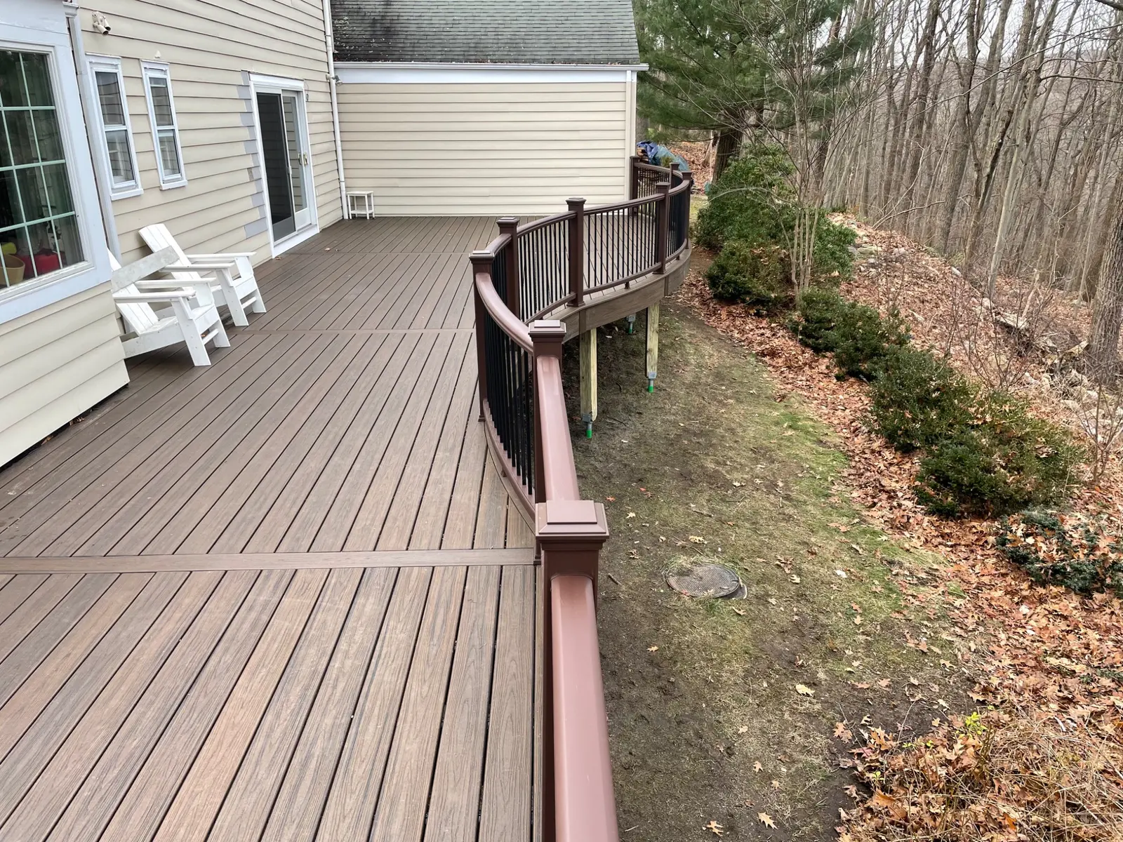 Large curved composite deck with brown railing and black balusters