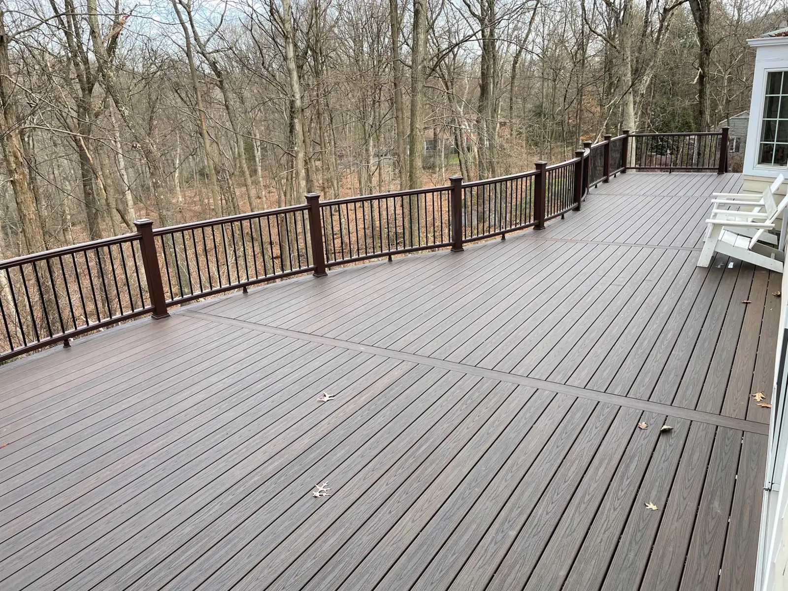 Wide view of the curved deck and wooded backyard