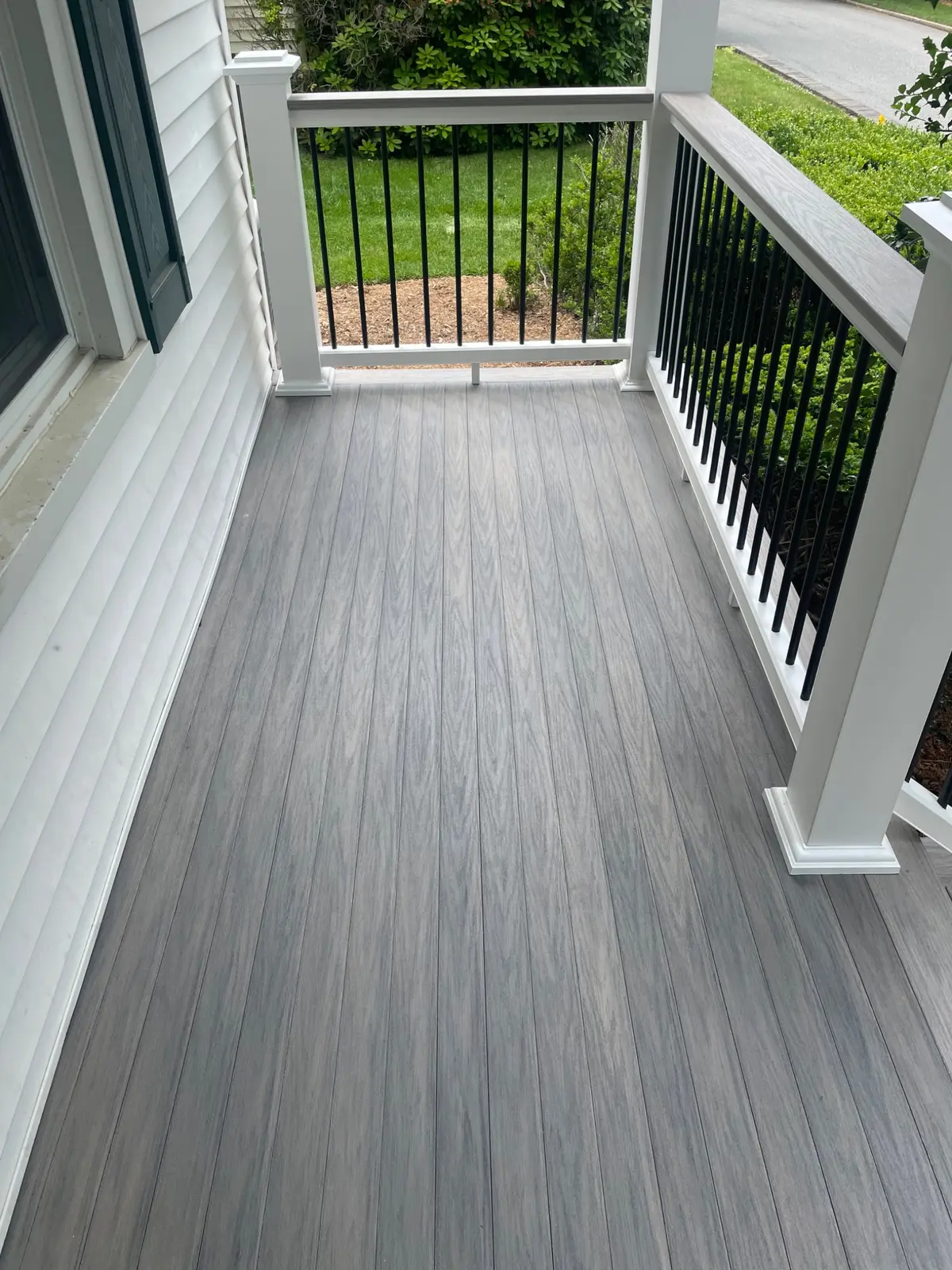 Composite porch surface with white posts and black balusters