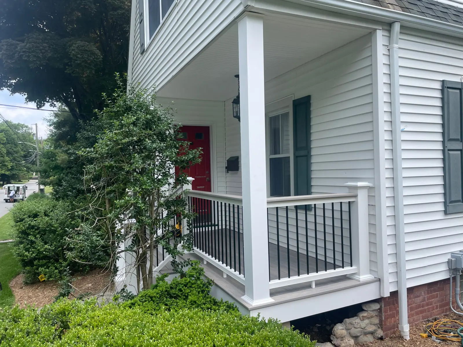 Small covered front porch with composite decking and white railing